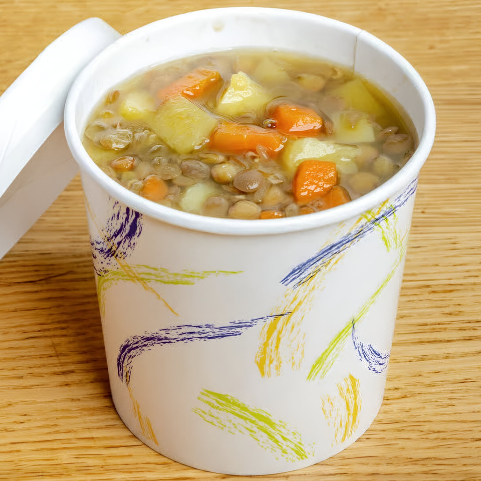 Hearty lentil soup with carrots and potatoes in a branded Soup Maison to-go cup.