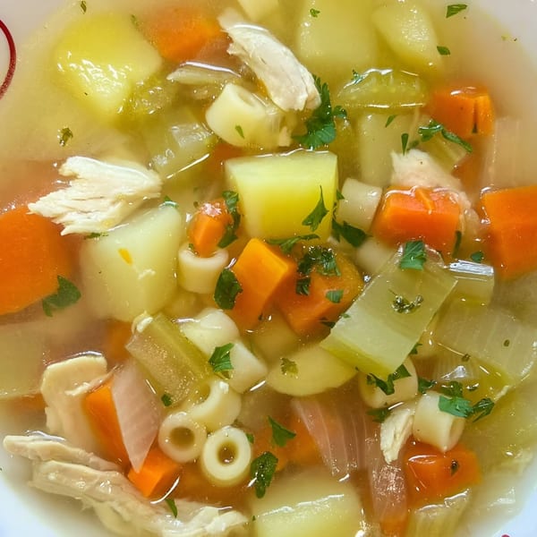 Close-up of Soup Maison's chicken noodle soup with carrots, potatoes, celery, and parsley.